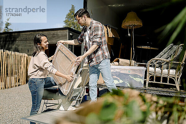 Mann und Frau beim Entladen von Gemälden aus einem Lastwagen an einem sonnigen Tag