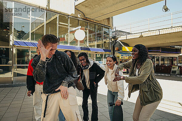 Multirassische Freunde bejubeln einen jungen Mann  der auf der Straße tanzt