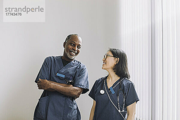Glückliche Gesundheitsexperten  die sich gegenseitig an einer weißen Wand im Krankenhaus ansehen
