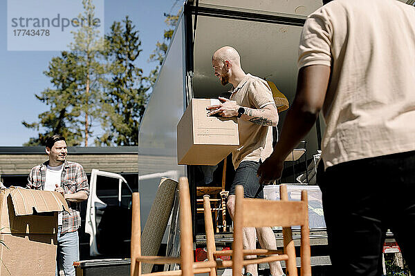 Mitarbeiter einer Lieferfirma helfen einem Mann beim Entladen von Kisten aus einem Lastwagen