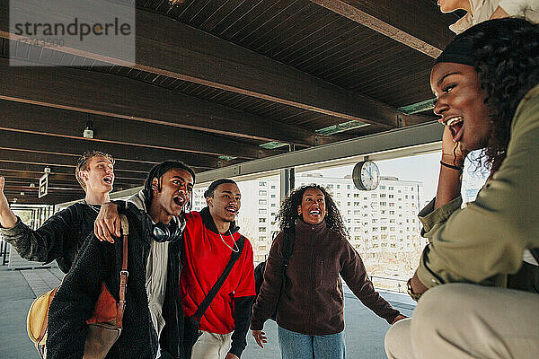 Verspielte multirassische junge Freunde singen auf dem Bahnsteig