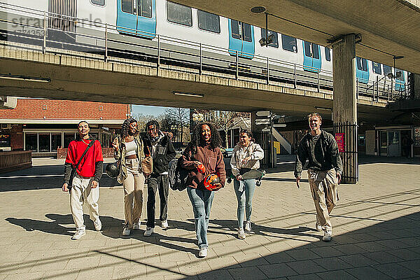 Glückliche multirassische junge Freunde gehen zusammen auf der Straße unter der Brücke