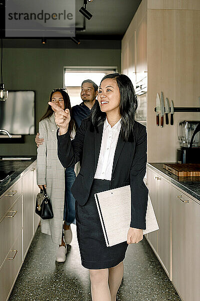 Immobilienmakler  der Kunden die Küche eines neuen Hauses zeigt