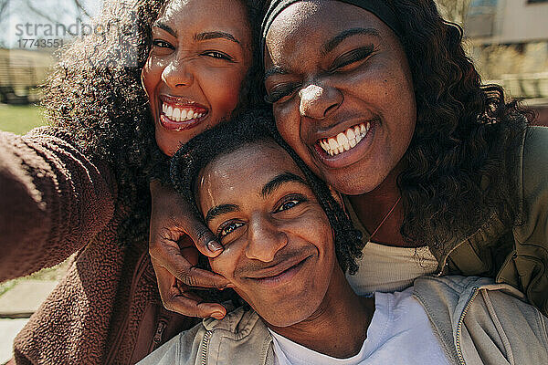 Glückliche junge Freunde machen Gesichter  während sie zusammen ein Selfie machen