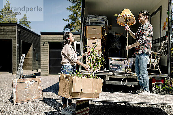 Ehepaar entlädt an einem sonnigen Tag Kartons vom Lastwagen