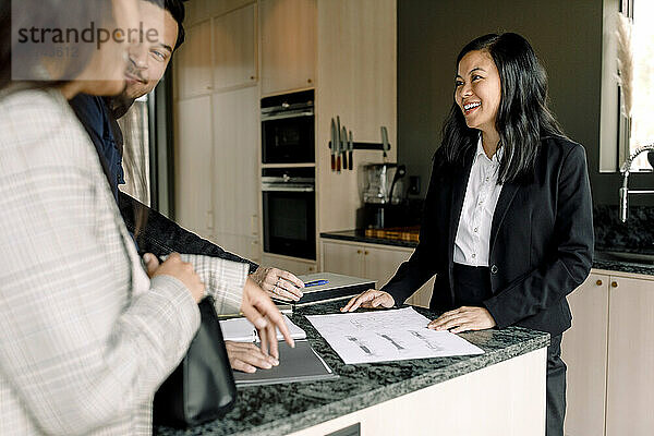 Lächelnder Immobilienmakler  der den Kunden die Unterlagen des neuen Hauses erklärt