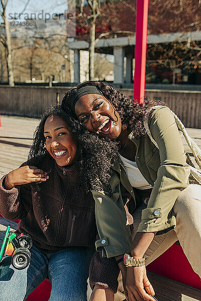 Porträt von glücklichen multirassischen Freundinnen  die zusammen auf einer Bank sitzen