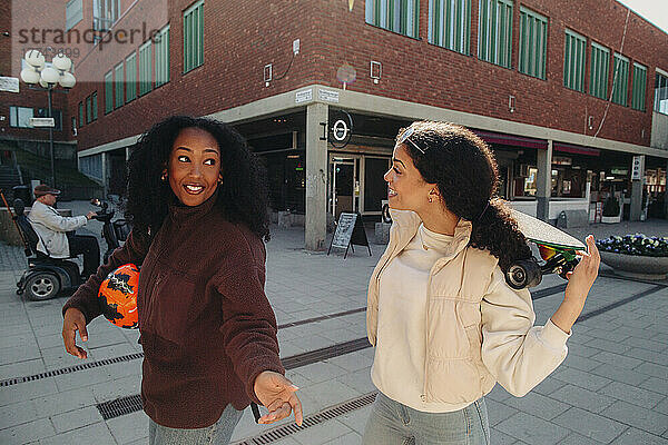 Junge Frau im Gespräch mit einer Freundin beim Gehen auf der Straße