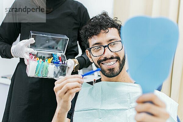 Zahnarzt mit Patient  der eine Metallspange wählt  Patient mit Zahnarzt  der ein Gummiband wählt  der eine Zahnspange wählt