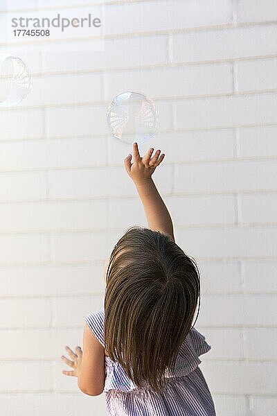 Ein dreijähriges Mädchen jagt Seifenblasen