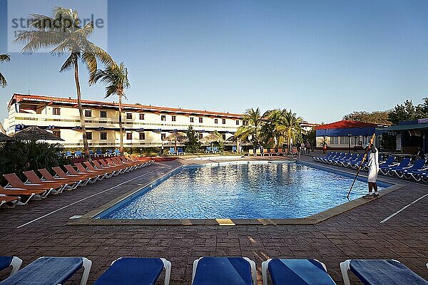 Mann reinigt Swimming Pool  Sonnenliege  hinten Hotelgebäude  Sonnenschirm  Cocos-Palme (Cocos nucifera)  Hotel Club Amigo Costasur  Trinidad  Provinz Trinidad  Kuba  Westindische Inseln  Karibik  Mittelamerika