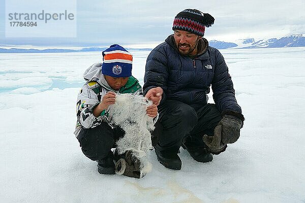 Eskimo zeigt seinem Sohn Babyfell von Bartrobbe  Ellesmer  Inuit  Ureinwohner  Island  Kanada  Nordamerika