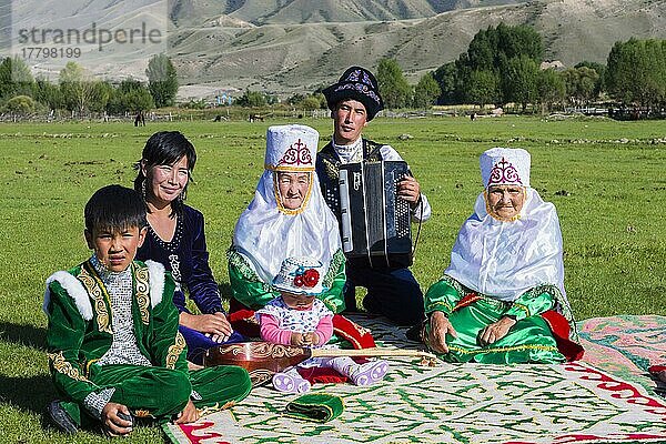 Kasachische Familie in traditioneller Kleidung  die der Musik eines Akkordeonspielers lauscht  Nur für den redaktionellen Gebrauch  Dorf Sati  Tien-Shan-Gebirge  Kasachstan  Asien