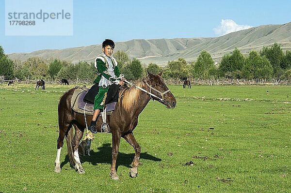 Kasachischer Junge in traditioneller Kleidung auf einem Pferd  Dorf Sati  Tien-Shan-Gebirge  Kasachstan  Asien
