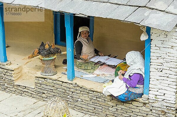 Zwei alte nepalesische Frauen sitzen in der Tür und nähen  Bergdorf Dhampus  Nepal  Asien