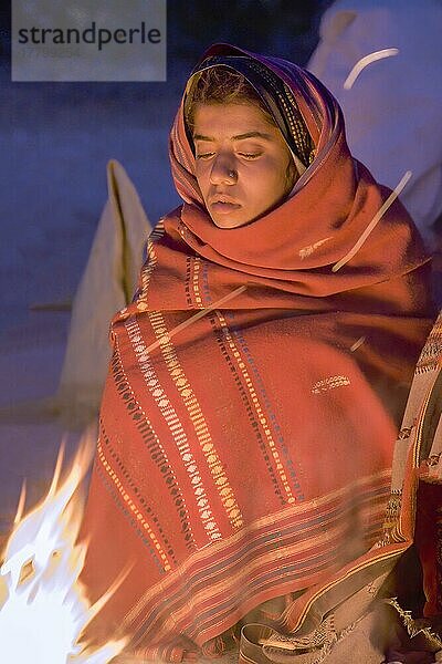 Junges Mädchen vom Stamm der Fakirani  sitzend neben einem Holzfeuerlager am frühen Morgen  Great Rann of Kutch Wüste  Gujarat  Indien  Asien