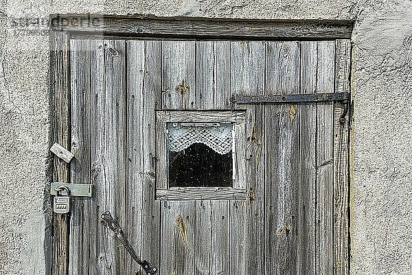 Alte braune Holztür mit Vorhängeschloss  Fenster und kleiner Gardine  Detailaufnahme  Fischerstelle  saisonal bewohntes Dorf an der Küste  Norebod Fiskeläge  Südgotland  Insel Gotland  Schweden  Europa