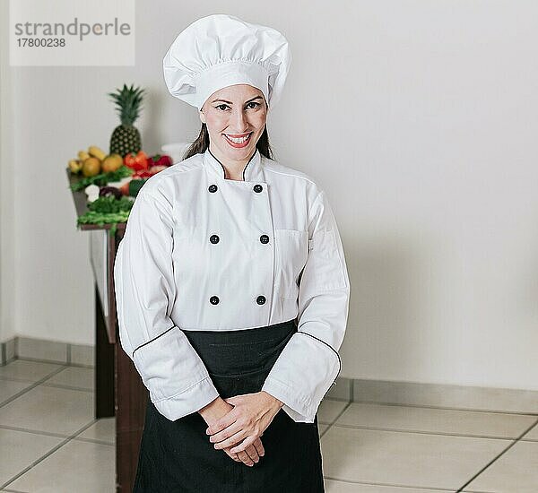 Porträt einer Ernährungsberaterin in Uniform mit frischem Gemüse auf dem Tisch  Eine Ernährungsberaterin mit einem Tisch voller Gemüse  Porträt einer Köchin umgeben von frischem Gemüse