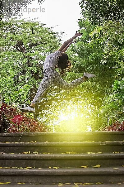 Mädchen springt umgeben von Bäumen  Konzept der glücklichen Mädchen springen