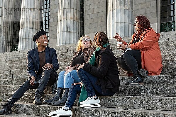 Eine Gruppe von Freunden  die sich auf der Treppe ihrer Universität angeregt unterhalten