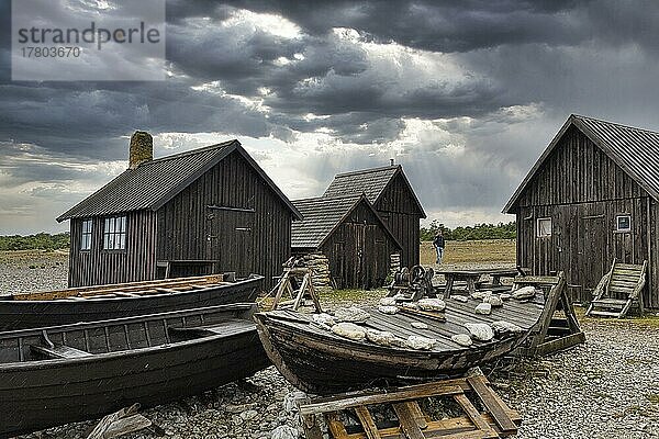 Alte Fischerhütten und Boote  traditionelle Fischerstelle  Fischerdorf  Helgumannen Fiskeläge  dramatischer Wolkenhimmel  Insel Fårö  Farö  Gotland  Ostsee  Schweden  Europa