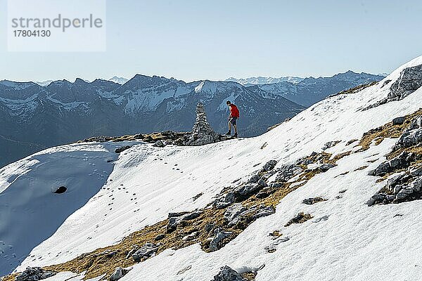 Bergsteiger neben einem Steinmännchen  vor verschneiten Bergen des Rofan  Wanderweg zum Guffert mit erstem Schnee  im Herbst  Brandenberger Alpen  Tirol  Österreich  Europa