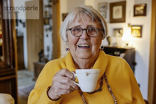 Seniorin hält zuhause lächelnd eine Tasse Kaffee in der Hand  Bocholt  Nordrhein-Westfalen  Deutschland  Europa
