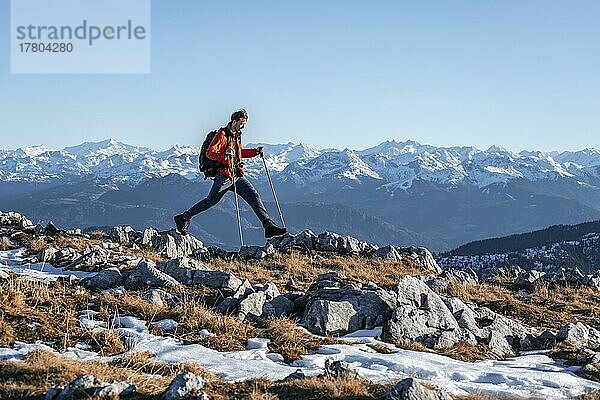 Bergsteiger macht einen großen Schritt  vor Bergpanorama  Wanderweg am Guffertstein  hinten Alpenhauptkamm mit Großvenediger  im Herbst  Brandenberger Alpen  Tirol  Österreich  Europa