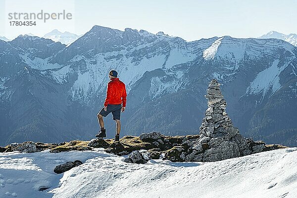 Bergsteiger neben einem Steinmännchen  vor verschneiten Bergen des Rofan  Wanderweg zum Guffert mit erstem Schnee  im Herbst  Brandenberger Alpen  Tirol  Österreich  Europa