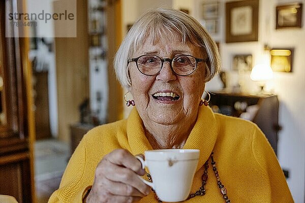 Seniorin hält zuhause lächelnd eine Tasse Kaffee in der Hand  Bocholt  Nordrhein-Westfalen  Deutschland  Europa