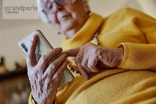 Seniorin schreibt zuhause eine Nachricht auf ihrem Smartphone  Bocholt  Nordrhein-Westfalen  Deutschland  Europa