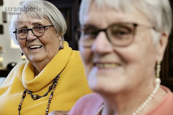 Zwei Seniorinnen  Schwestern  lachen zuhause freundlich in die Kamera  Bocholt  Nordrhein-Westfalen  Deutschland  Europa