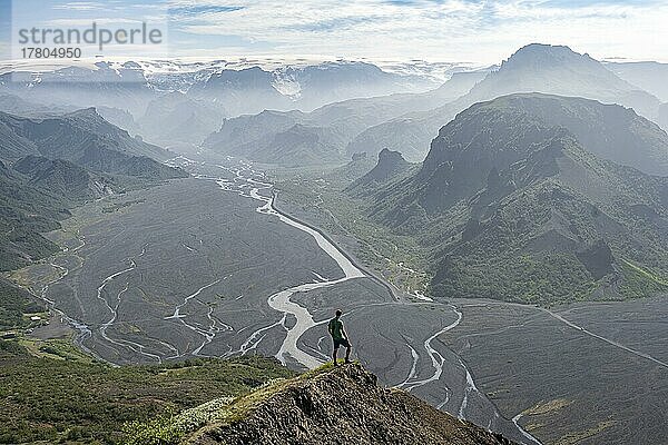 Wanderer vor Berglandschaft  Berge mit Gletscher Mýrdalsjökull und Gletscherfluss Krossá in einem Bergtal  Gipfel Valahnúkur  wilde Natur  Isländisches Hochland  Þórsmörk  Suðurland  Island  Europa
