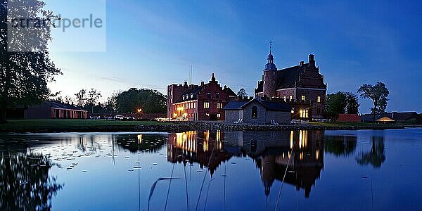Beleuchtetes Schloss spiegelt sich in einem ruhigen Gewässer  Broholm Slot  Fünen  Dänemark  Europa