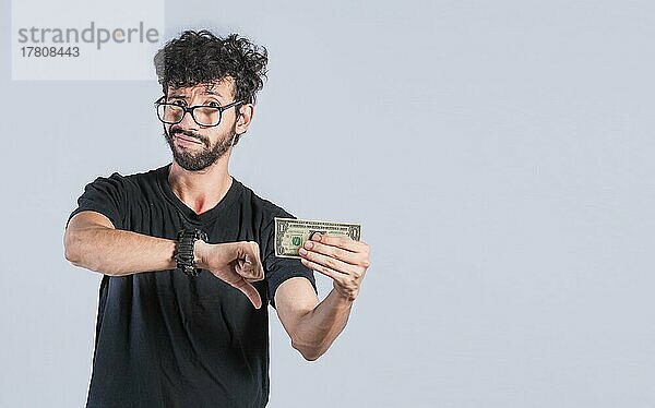 Traurige Person  die eine Banknote mit dem Daumen nach unten hält  Trauriger Mann mit einer Dollarnote  Konzept eines Mannes mit Geldproblemen
