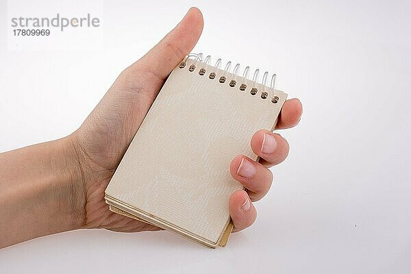 Hand hält ein Spiral-Notizbuch auf einem weißen Hintergrund