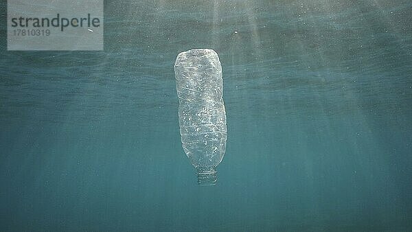 Plastikverschmutzung  weggeworfene Plastikflasche  die unter der Oberfläche des Wassers in den Sonnenstrahlen bei Sonnenuntergang treibt. Plastikmüll Umweltverschmutzung Problem im Ozean. Baklighting. Rotes Meer  Ägypten  Afrika