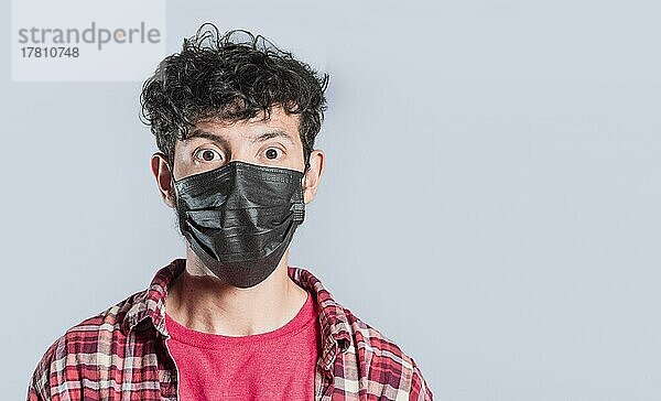 Close-up of handsome guy wearing protective mask  Close up of latin person wearing surgical mask isolated  Close-up of person wearing surgical mask on isolated background