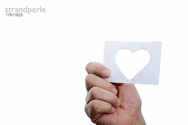 Hand  die ein aus Papier ausgeschnittenes Herz auf einem weißen Hintergrund hält