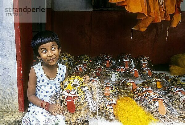 Ein Mädchen posiert mit einer Pulikali Maske in ihrer Hand in Thrissur oder Trichur  Kerala  Indien  Asien