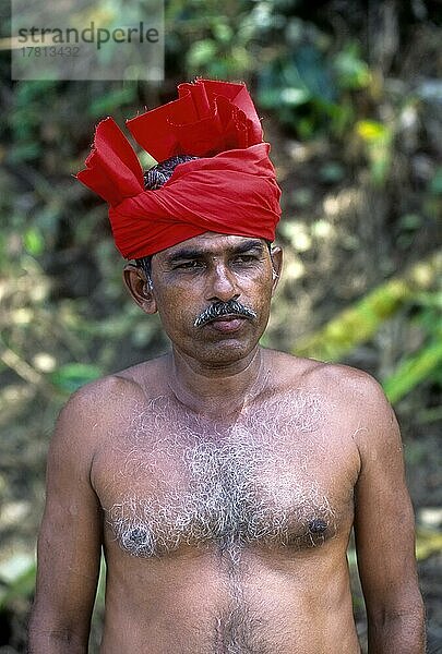 Ein Mann ohne Hemd mit rotem Turban  Kerala  Indien  Asien