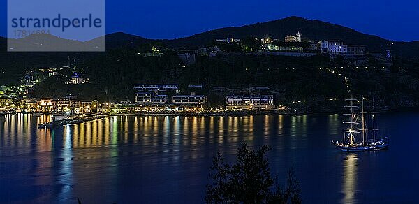 Panoramablick auf Porto Azzurro mit beleuchtete Hafenpromenade bei Abendstimmung während Blaue Stunde  rechts oben im Hintergrund Gefängnis Casa di Reclusione House of Detention  Porto Azzurro  Elba  Toskana  Italien  Europa