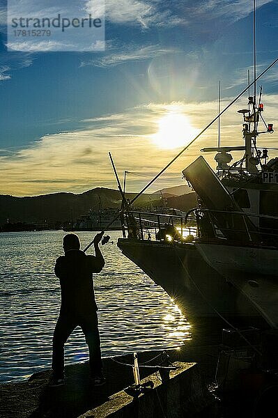 Gegenlichtaufname von Silhouette von Angler wirft Angel Angelrute in Hafen aus kurz vor Sonnenuntegrang  Portoferraio  Elba  Toskana  Italien  Europa