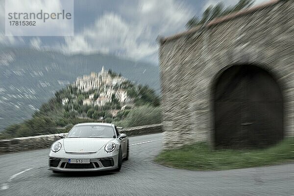 Dynamisches Foto mit Geschwindigkeitseffekt von Supercar Sportwagen Porsche GT3 in enge Kurve von historischer Streckenabschnitt von Rallye Monte Carlo 1965  im Hintergrund La Roquette-sur-Var  Département Alpes-Maritimes  Region Provence-Alpes-Côte d?Azur  Frankreich  Europa