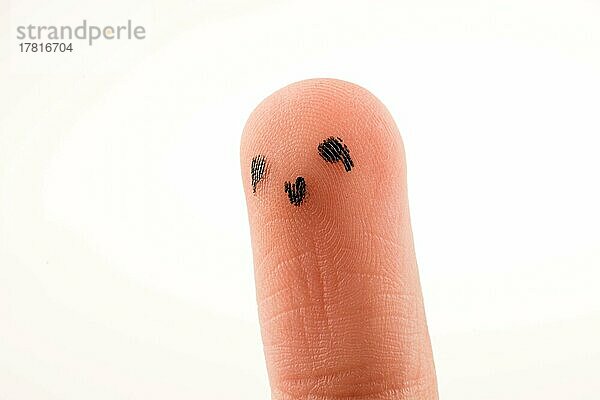 Schwarze Punkte  die ein Gesicht auf der Fingerkuppe bilden