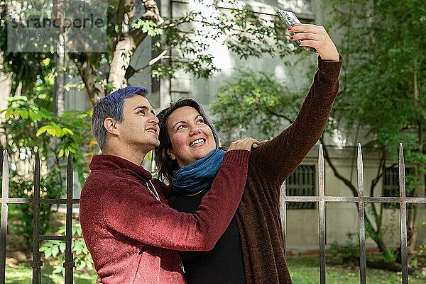 Zwei Freunde machen Selfies im Freien. Er hat blaue Haare