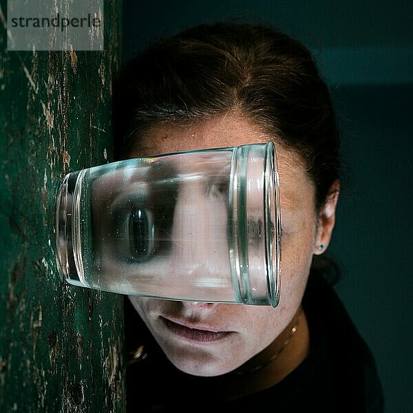 Gruseliges Gesicht einer Frau  gespiegelt in einem Wasserglas