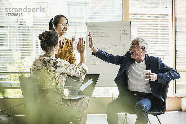 Glückliche Geschäftskollegen  die sich im Büro gegenseitig High-Five geben