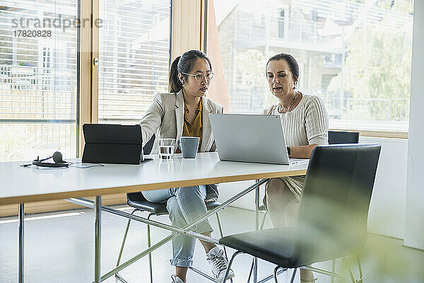 Reife Geschäftsfrau mit Kollegin diskutiert am Laptop im Büro