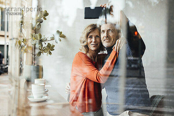Lächelnder Mann und Frau machen Selfie per Smartphone im Café